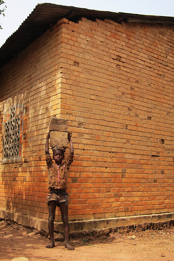 Child carrying bricks, Duru, DR Congo